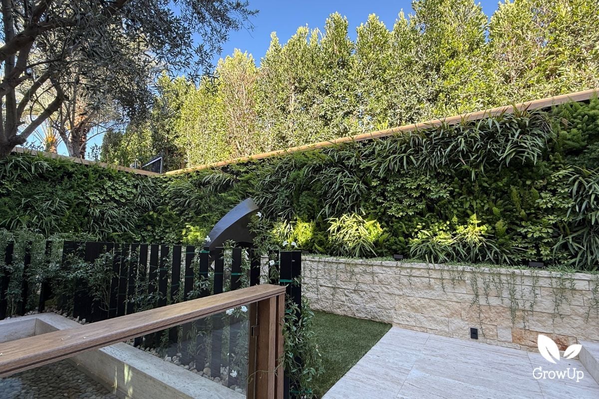 Large living greenwall in luxury garden with a sculpture