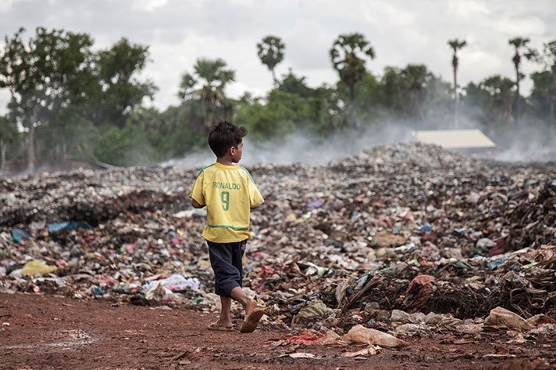 a child walking through a trash dump site